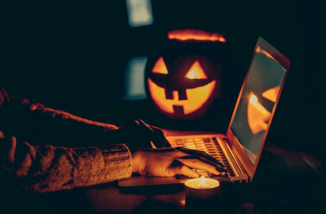 pumpkin and person typing on laptop in dark