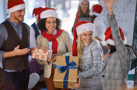 staff enjoying christmas celebrations holding gifts and wearing santa hats