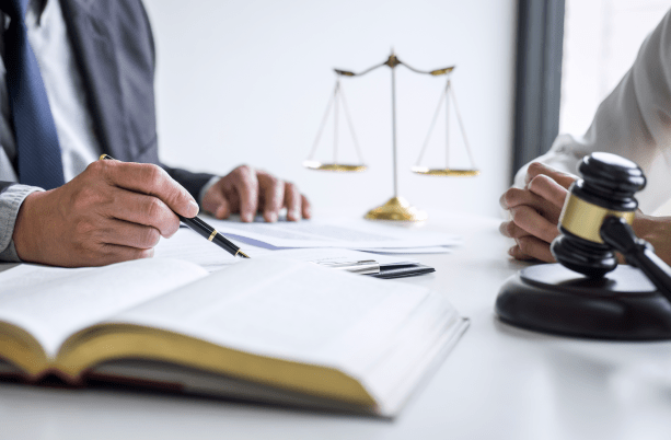 hand holding pen, a book and gavel in foreground