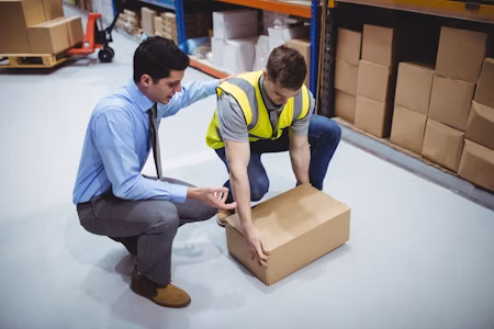 Man being shown how to correctly lift a box.