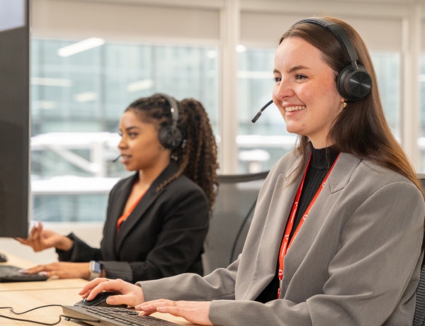 two female customer support agents attending a user call smiling