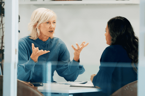 An employer providing feedback to an employee in a meeting room