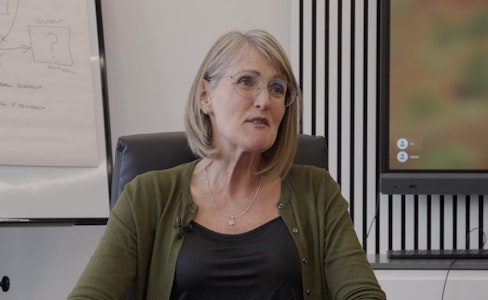 Woman with bobbed hair sitting down in an office boardroom