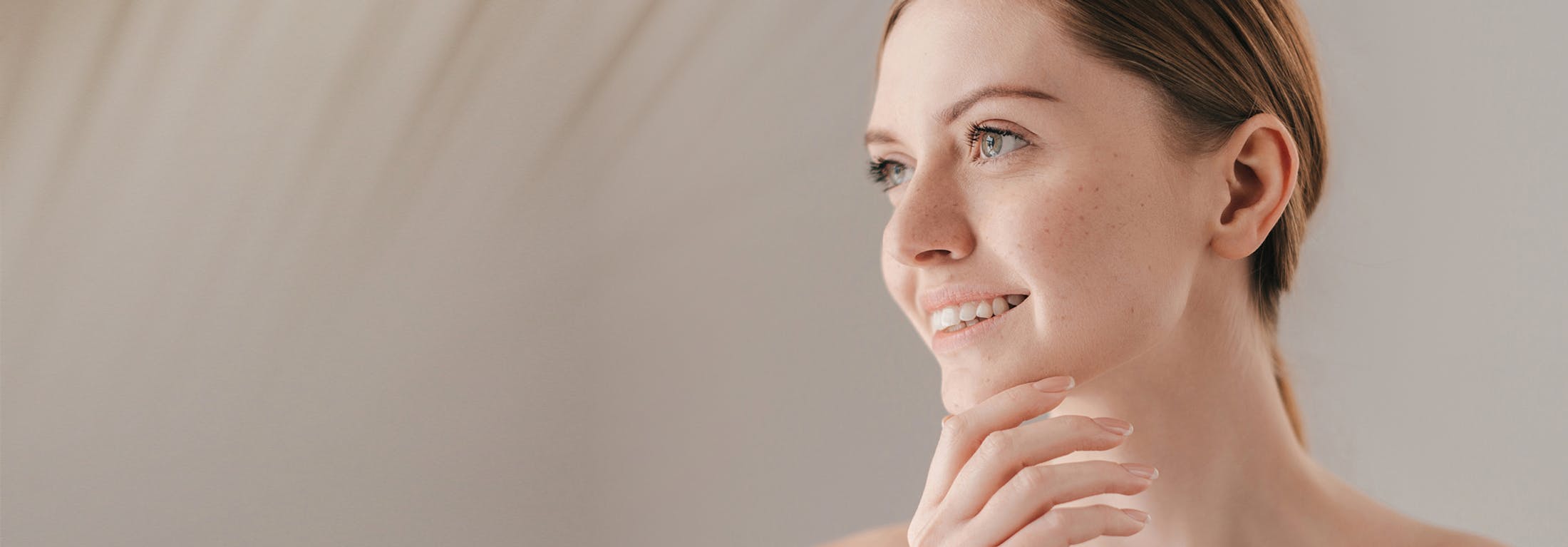 woman with hair back touching chin