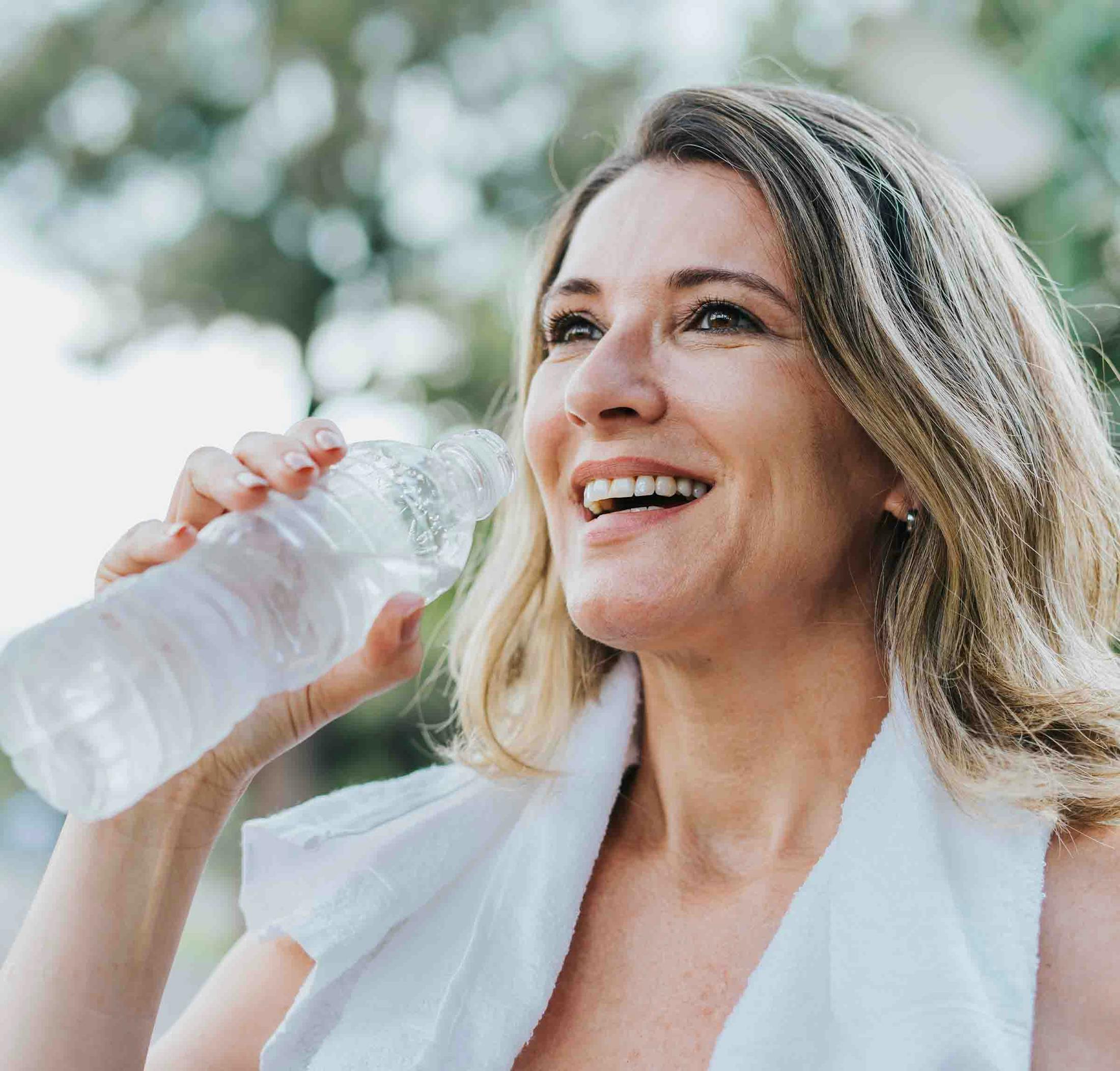 Woman happily drinking water after hormone therapy for women in Denver