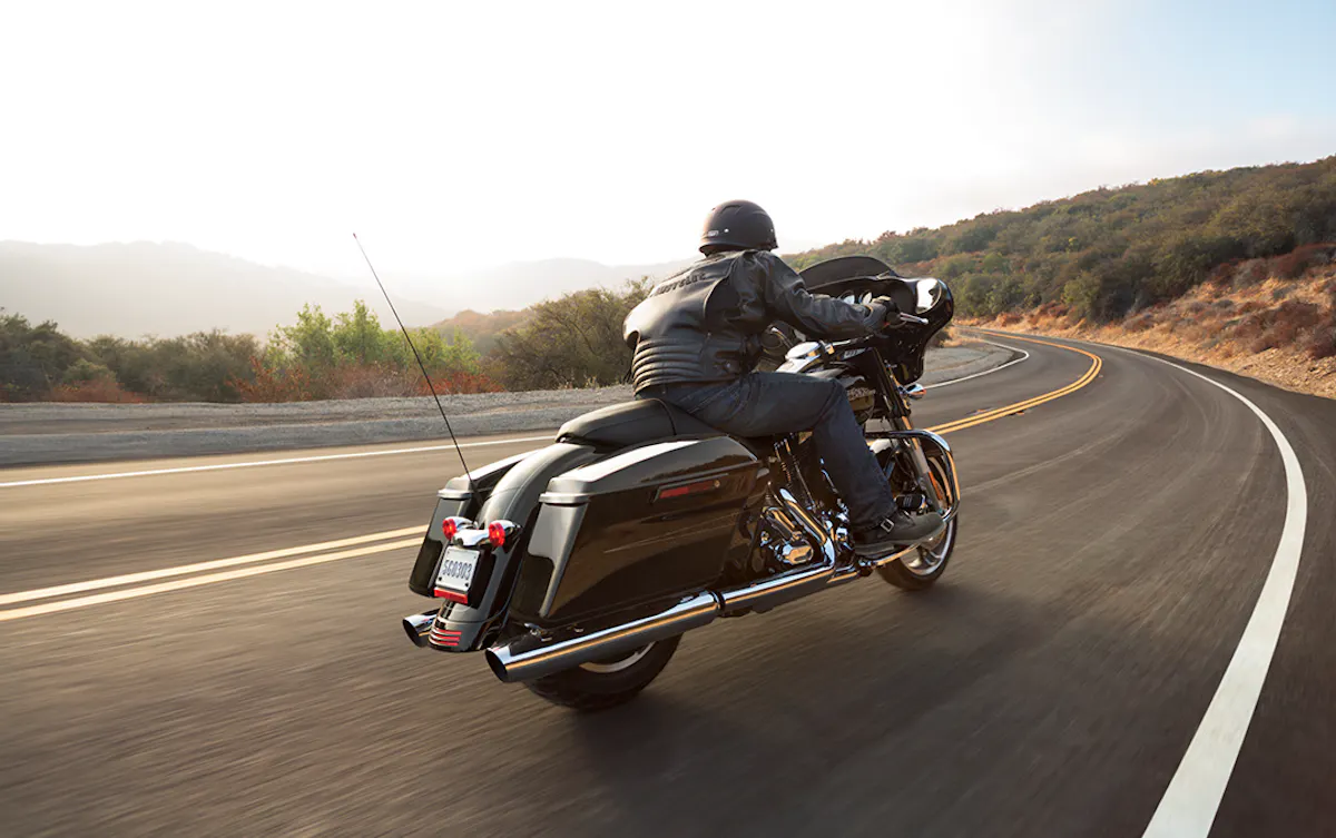 Harley Davidson motorbike driving down 2 lane rural road