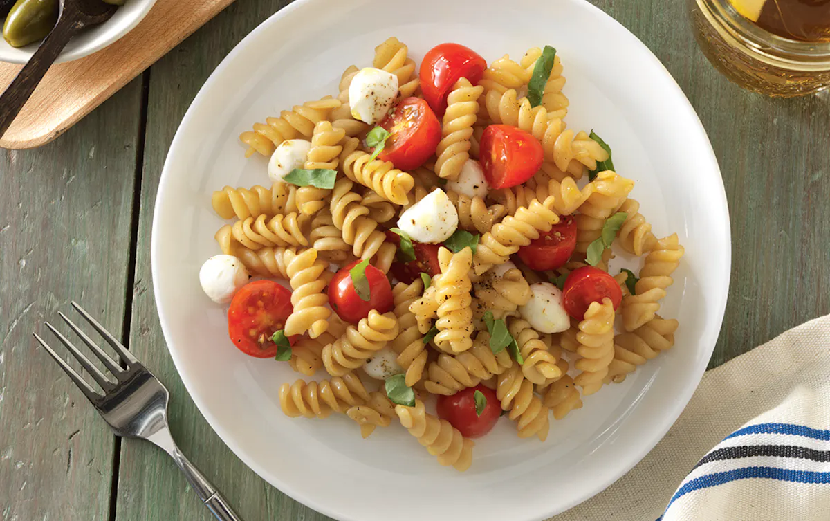 Plate of caprese rotini pasta on rustic table