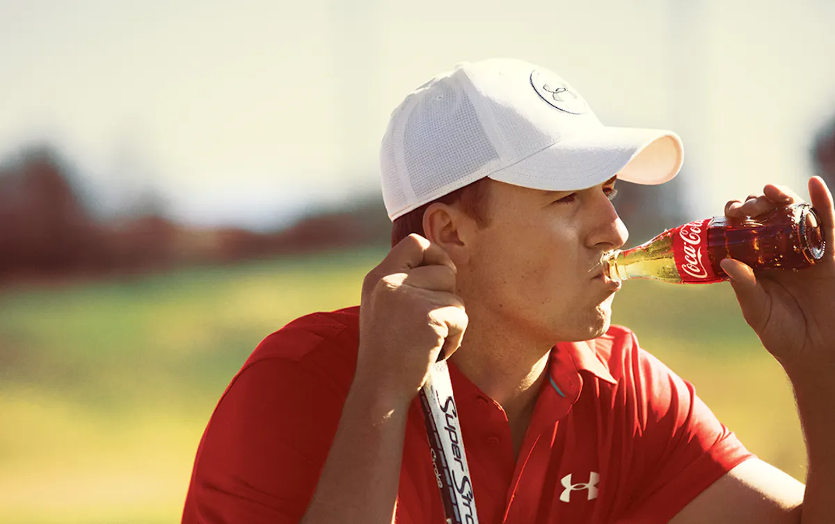 Man drinking a bottle of Coca-Cola in an outdoor sports environment