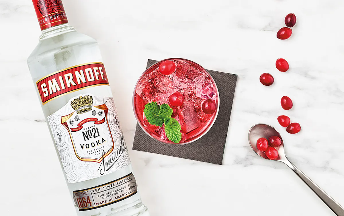 Bottle of Smirnoff vodka next to a cranberry cocktail
