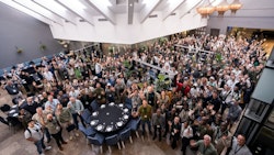 A photo from EarthRanger's user conference, taken from above, a diverse group of individuals is waving at the camera.