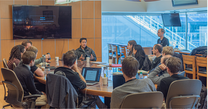 A number of individuals at a conference table, concentrating on one speaker.