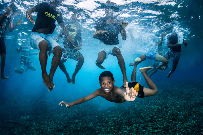 A boy swimming underwater smiles at the camera.