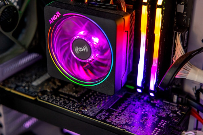 A closeup of the internals of a computer, lit with rainbow colored LED lights and including a spinning fan.