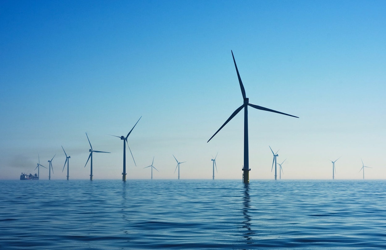 Windmills along a body of water.