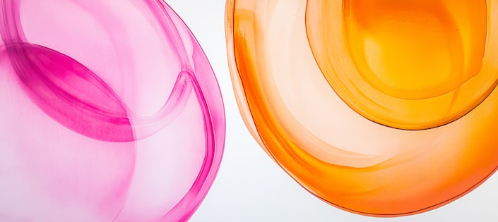 Swirling shapes in shades of pink and orange blend artistically against a bright, neutral surface