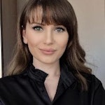 Bu, uzun, dalgalı kahverengi saçlı bir kadının görüntüsüdür. Uzun kollu ve yuvarlak yakalı siyah bir gömlek giyiyor. Yüz ifadesi sakin ve rahattır ve gözleri uzaklara odaklanmıştır. Küçük bir burnu var ve dudakları sanki bir şey söylemek üzereymiş gibi hafifçe ayrılmış. Saçları ortadan ayrılmış ve sırtından aşağı dökülüyor. Kendinden emin ve sakin görünüyor. Arka plan nötr bir renkte ve ışık yumuşak ve sıcak. Bu görüntü huzur ve dinginlik hissi veriyor.