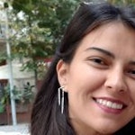 Kahverengi saçlı genç bir kadın dışarıda duruyor ve kameraya genişçe gülümsüyor. Gözleri neşeli bir ifadeyle kapalı ve dudakları hoş bir sırıtışla kıvrılmış. Üzerinde beyaz bir gömlek ve mavi bir kot pantolon var ve kollarını iki yana açmış. Arka planda beyaz bulutlarla bezeli mavi bir gökyüzü var. Rahat ve mutlu görünüyor, memnuniyetin mükemmel bir görüntüsü.