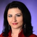 Bu, uzun siyah saçlı genç bir kadının görüntüsüdür. Üzerinde hafif bol parlak kırmızı bir gömlek var. Gözleri kapalı ve dudakları hafifçe ayrık, sanki rahatlamak için bir an ayırıyormuş gibi. Başı hafifçe eğik ve kollarını göğsünün üzerinde kavuşturmuş. Kendinden emin ve rahat bir duruşu var. Saçları omuzlarına dökülen yumuşak, doğal dalgalarla şekillendirilmiş. Yirmili yaşlarında olduğu anlaşılıyor ve yüzünde sıcak ve davetkâr bir ifade var. Bu anda dingin ve mutlu görünüyor.