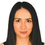 Açık tenli ve açık kahverengi saçlı genç bir kadın doğrudan kameraya bakmaktadır. Üzerinde siyah desenli beyaz bir tişört var. Gözleri hafifçe kapalı ve dudakları rahat bir ifadeyle hafifçe ayrılmış. Boynuna altın bir kolye ve bir çift küçük halka küpe takıyor. Saçları düzgün bir şekilde toplanmış ve yüzü güneşin ışığıyla çerçevelenmiş. Yüz ifadesi sakin ve huzurlu, duruşu kendinden emin ve rahat. Bakışları hem davetkâr hem de esrarengiz.