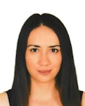 Açık tenli ve açık kahverengi saçlı genç bir kadın doğrudan kameraya bakmaktadır. Üzerinde siyah desenli beyaz bir tişört var. Gözleri hafifçe kapalı ve dudakları rahat bir ifadeyle hafifçe ayrılmış. Boynuna altın bir kolye ve bir çift küçük halka küpe takıyor. Saçları düzgün bir şekilde toplanmış ve yüzü güneşin ışığıyla çerçevelenmiş. Yüz ifadesi sakin ve huzurlu, duruşu kendinden emin ve rahat. Bakışları hem davetkâr hem de esrarengiz.
