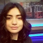 Bu, uzun, koyu kahverengi saçlı bir kadının resmi. Yüzünde parlak, neşeli bir gülümseme var. Mutlu ve memnun görünüyor. Gözleri kapalı ve pembe yanakları var. Açık pembe bir kolye ile beyaz bir gömlek giyiyor. Saçları gevşek bukleler halinde şekillendirilmiş ve sırtından aşağı dökülüyor. Yirmili yaşlarının sonunda ya da otuzlu yaşlarının başında gibi görünüyor. Sıcak ve davetkâr bir duruşu var ve gülümsemesi odayı aydınlatıyor gibi görünüyor. Birlikte vakit geçirmek isteyeceğiniz birine benziyor ve iyimserliği bulaşıcı.