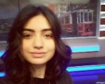 Bu, uzun, koyu kahverengi saçlı bir kadının resmi. Yüzünde parlak, neşeli bir gülümseme var. Mutlu ve memnun görünüyor. Gözleri kapalı ve pembe yanakları var. Açık pembe bir kolye ile beyaz bir gömlek giyiyor. Saçları gevşek bukleler halinde şekillendirilmiş ve sırtından aşağı dökülüyor. Yirmili yaşlarının sonunda ya da otuzlu yaşlarının başında gibi görünüyor. Sıcak ve davetkâr bir duruşu var ve gülümsemesi odayı aydınlatıyor gibi görünüyor. Birlikte vakit geçirmek isteyeceğiniz birine benziyor ve iyimserliği bulaşıcı.