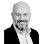Bu, geniş ve neşeli bir gülümsemeye sahip genç bir adamın yakın plan görüntüsüdür. Beyaz bir gömlek ve koyu mavi bir kravat takıyor ve gözleri kapalı. Saçları kısa ve düzgün, yüzü sıcak ve hoş bir ışıkla aydınlatılmış. Elleri kucağında duruyor ve dudakları parlak ve sevimli bir gülümseme şeklinde kıvrılmış. İfadesi mutluluk ve memnuniyet dolu bir hava taşıyor ve tüm yüzü neşe saçıyor. Genel olarak bu, iyi bir ruh hali içinde olduğu belli olan bir kişinin büyüleyici ve keyifli bir portresi.