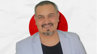 Bu, Japon bayrağının önünde gülümseyen bir adamın fotoğrafı. Geleneksel kıyafetler giydiği görülüyor, bu da kültürün bir parçası olduğunu gösteriyor. Bu resim Japonya'nın dilini ve kültürünü öğrenmenin önemini sembolize ediyor olabilir. Konuşma eğitimine katılarak Japon kültürü ve sosyal görgü kuralları hakkında bir fikir edinebiliriz. Bu, daha iyi bir anlayış ve iletişimin anahtarı olabilir ve Japonlarla anlamlı konuşmalar yapmamızı sağlayabilir. Dil öğrenmek, kültürü deneyimlemek ve topluma daha fazla entegre olmak için harika bir yoldur.