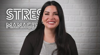 A woman explaining a stress management course. In the foreground she is giving academic information about stress management. woman standing in front of a brick wall with stress management sign, dark beige and silver style, progressive artist movement, smilecore, video montages, george stefanescu, chicano inspired, website --ar 16:9