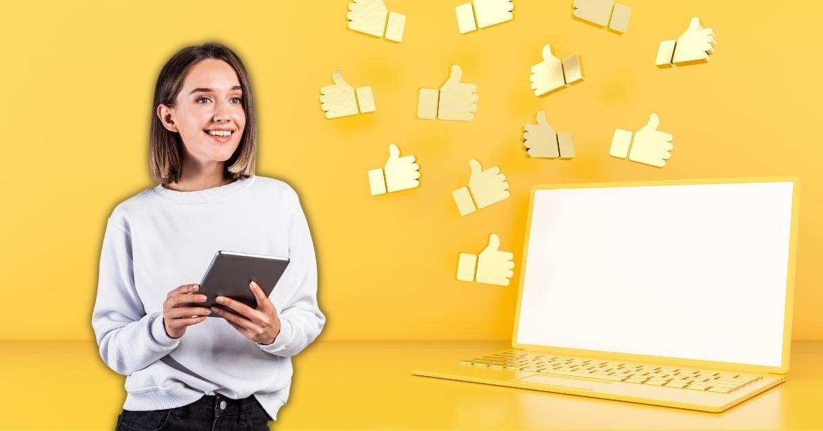 A woman is pictured smiling while holding a tablet computer. She is sitting in front of a laptop with a white screen, and her hands are positioned on the tablet, which has a brightly colored background. She has a bright yellow background to her, and her eyes are focused on the tablet. In the background, there is a group of thumbs-up symbols in different colors, including a white one on the top right and a yellow one on the bottom left. The woman is wearing a suit, and her hair is tied back. Her expression is one of joy and contentment.