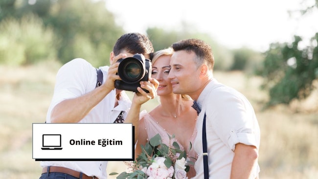 Bu görüntü bir düğün fotoğrafçılığı eğitim seansını göstermektedir. Bir adam elinde bir buket çiçek tutan bir kadının fotoğrafını çekiyor. Adamın beyaz gömlek giymesi ve papyon takması bunun resmi bir etkinlik olduğunu gösteriyor. Buketin ve tabelanın yakın çekimi, çiftin çekim için poz verdiğini gösteriyor. Kaliteli bir düğün fotoğrafçılığının harika bir örneği.