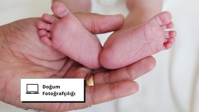Bir kişinin elinde tuttuğu yeni doğmuş bir bebeğin ayaklarının yakın çekimi. Minik ayaklar yeni doğmuş bir bebeğin narin cildiyle yumuşak ve pürüzsüzdür. Tırnaklar küçük ve sivri, ayak parmakları ve el parmakları mükemmel biçimde şekillenmiş. Kişinin eli bebeğin ayaklarını kucaklarken, arka plan arka planda bir tabelanın göründüğü kapalı bir ortamdır. Görüntü, yeni bir hayatın güzelliğini ve masumiyetini ve bir ebeveyn ile çocuk arasındaki bağı yakalıyor.