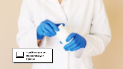 Bu görselde mavi eldiven giymiş ve elinde bir kap tutan bir kişi görülmektedir. Bu kişi muhtemelen sterilizasyon ve dezenfeksiyon eğitimi vermekte ve kabın bakteri ve diğer kirleticilerden arındırılmasını sağlamaktadır. Kişinin eldivenlerinin yakın çekimi, bu süreçte koruyucu donanımın önemini göstermektedir. Bu kurs, ortamları hijyenik ve güvenli tutmak için gereklidir.