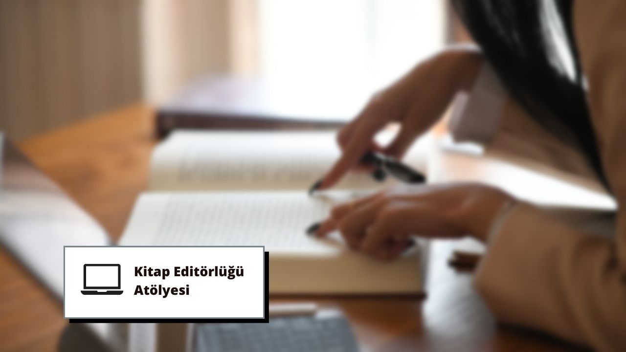 Sarı gömlek ve koyu renk pantolon giyen bir kadın, bir ofisteki masasında oturmuş, siyah bir kalemle bir kitaba yazı yazmaktadır. Sol elini masanın kenarına dayamış ve sağ eliyle kalemi tutarak kitabın açık sayfasına yazmaktadır. Odadaki ışık yüzünde parlıyor, kitabı ve masayı aydınlatıyor. Yüzü odaklanmış ve konsantre olmuş, gözleri yazdığı sayfaya bakıyor. Kitap, yazdığı sayfaya kadar açık ve kalem kâğıt üzerinde hareket ederek sayfaya sözcükler yazıyor.
