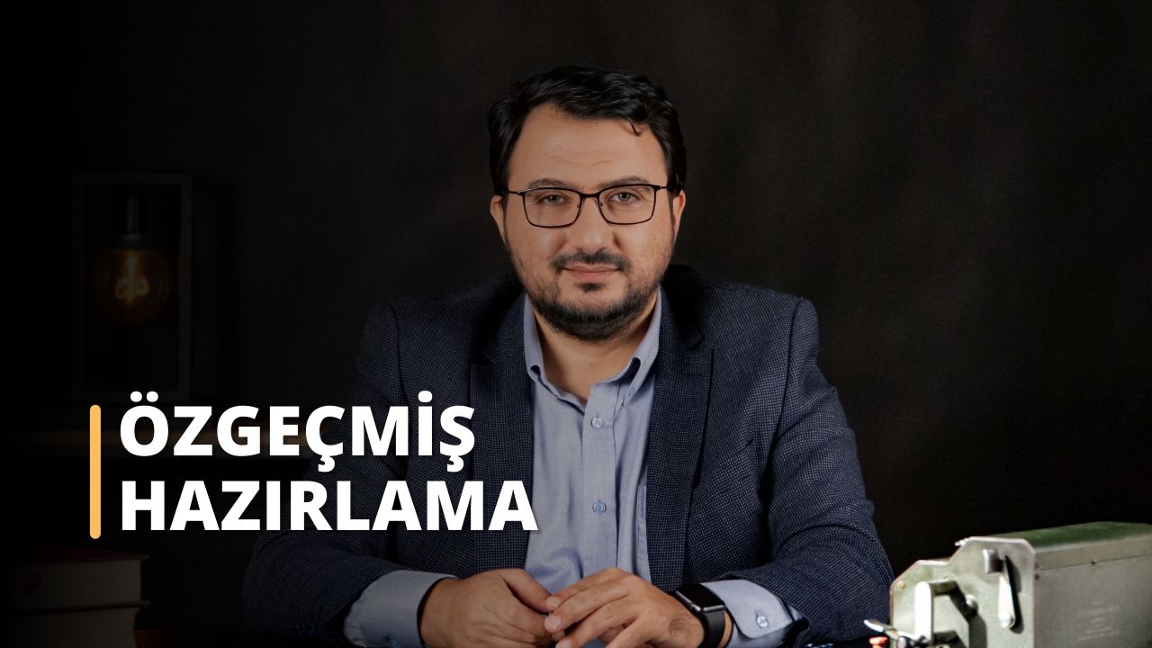 Resimde muhtemelen bir CV görüşmesine hazırlanan takım elbiseli bir adam görülüyor. Gözlüklü, sakallı ve düğmeli gömleğiyle kendinden emin ve iyi giyimli görünüyor. Arka planda metal bir kutunun yakın çekimi, bir saat ve bir kol görülebiliyor. Bu görüntü, bir CV görüşmesine nasıl hazırlanılması gerektiğine dair mükemmel bir örnektir.