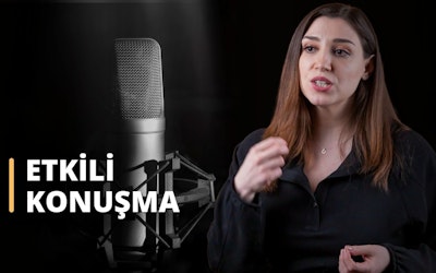 Bu görüntüde mikrofona konuşan bir kadın görülmekte olup, Doğru ve Etkili Konuşma Teknikleri Eğitimine katıldığını göstermektedir. Siyah bir gömlek giymiş, kolye takmış ve uzun saçlarıyla kursu ciddiye aldığını gösteriyor. Arka planda siyah beyaz bir fotoğraf var, bu da kursta konuşurken doğru tonda konuşmanın öneminin tartışıldığını gösteriyor. Bir konuşmacının yakın çekimi de kurstaki ses unsurunun önemini göstermektedir. Son olarak, konuşurken fiziksel jest ve hareketlere duyulan ihtiyacı vurgulayan bir elin yakın çekimi görülmektedir. Bu kurs, bireylerin doğru ve etkili konuşmayı öğrenmelerine yardımcı olmak için tasarlanmıştır, böylece kalıcı bir izlenim bırakabilir ve çabalarında başarılı olabilirler.