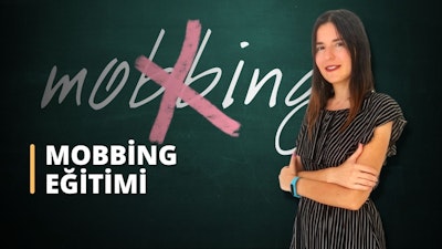 Bir kadın kara tahtanın önünde duruyor. Kollarını kavuşturmuş ve yüzünde şaşırtıcı derecede sıcak bir gülümseme var. Uzun, siyah saçları arkaya toplanmış ve üzerinde rahat, açık renkli bir gömlek var. Kara tahtanın üzerinde beyaz bir metin ve farklı renklerde birkaç şekil ve diyagram yazılı. Kadın kendinden emin ve memnun görünüyor, önündeki tahtada yazılı olan bilgileri bir an için kavrıyor. Görüntü kara tahtanın yakın çekimidir ve metnin ve diyagramların karmaşık ayrıntılarını göstermektedir. Kadının varlığıyla çerçevelenen genel kompozisyon, çevreye benzersiz bir bakış açısı sağlıyor.