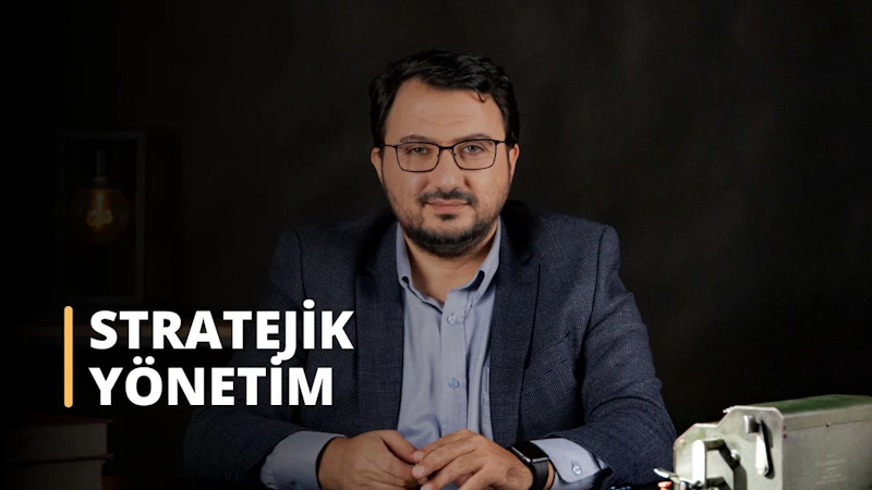 Bu görsel, Stratejik Yönetim üzerine çevrimiçi bir kursa aittir. Resimde takım elbise giymiş, masa başında oturan bir adam görülüyor. İzleyici ön planda metal bir kutunun, bir saatin, bir kişinin gözlerinin, düğmeli bir gömleğin ve bir adamın yüzünün yakın çekimini görebilmektedir. Arka planda da beyaz bir metnin yakın çekimi bulunmaktadır. Stratejik Yönetim dersi, öğrencilere etkili iş stratejileri planlamak ve uygulamak için gerekli bilgi ve araçları sağlayacaktır. Bu ders sayesinde öğrenciler potansiyel iş fırsatlarının nasıl değerlendirileceğini, stratejik planların nasıl geliştirileceğini ve risk ve belirsizliklerin nasıl yönetileceğini öğreneceklerdir. Ayrıca, rekabet ortamını nasıl değerlendireceklerini, şirketlerinin rekabet avantajlarını nasıl belirleyeceklerini ve bir rekabet stratejisi nasıl geliştireceklerini anlayacaklardır. Buna ek olarak, öğrenciler stratejik yönetim ile finans, pazarlama ve operasyonlar gibi diğer işletme fonksiyonları arasındaki ilişkiyi keşfedeceklerdir. Nihayetinde, bu ders öğrencileri başarılı stratejik yöneticiler olmak için gerekli becerilerle donatacaktır.