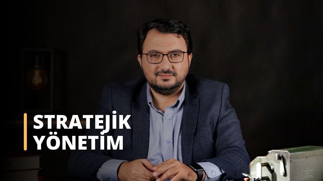 Bu görsel, Stratejik Yönetim üzerine çevrimiçi bir kursa aittir. Resimde takım elbise giymiş, masa başında oturan bir adam görülüyor. İzleyici ön planda metal bir kutunun, bir saatin, bir kişinin gözlerinin, düğmeli bir gömleğin ve bir adamın yüzünün yakın çekimini görebilmektedir. Arka planda da beyaz bir metnin yakın çekimi bulunmaktadır. Stratejik Yönetim dersi, öğrencilere etkili iş stratejileri planlamak ve uygulamak için gerekli bilgi ve araçları sağlayacaktır. Bu ders sayesinde öğrenciler potansiyel iş fırsatlarının nasıl değerlendirileceğini, stratejik planların nasıl geliştirileceğini ve risk ve belirsizliklerin nasıl yönetileceğini öğreneceklerdir. Ayrıca, rekabet ortamını nasıl değerlendireceklerini, şirketlerinin rekabet avantajlarını nasıl belirleyeceklerini ve bir rekabet stratejisi nasıl geliştireceklerini anlayacaklardır. Buna ek olarak, öğrenciler stratejik yönetim ile finans, pazarlama ve operasyonlar gibi diğer işletme fonksiyonları arasındaki ilişkiyi keşfedeceklerdir. Nihayetinde, bu ders öğrencileri başarılı stratejik yöneticiler olmak için gerekli becerilerle donatacaktır.