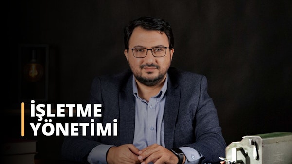 Bu resimde masa başında oturan, gözlüklü ve takım elbiseli bir adam görülüyor. Masanın üzerindeki metal kutudan ve muhtemelen bir zaman yönetimi aracı olarak kullanılan saatin yakın çekiminden de anlaşılacağı üzere, muhtemelen bir iş yönetimi eğitim kursuna katılıyor. Yüzü de yakından görülüyor ve düğmeli gömleği profesyonel bir atmosfere işaret ediyor. Bu görüntü, iş yönetimi eğitiminin önemini göstermek için mükemmeldir. Görevlerin üstesinden gelmek ve öncelikleri belirlemek için doğru araçlarla kendini hazırlamanın ve profesyonel bir imaj sergilemenin önemini vurguluyor. İşyerinde başarı için iş yönetimi eğitimi şarttır.