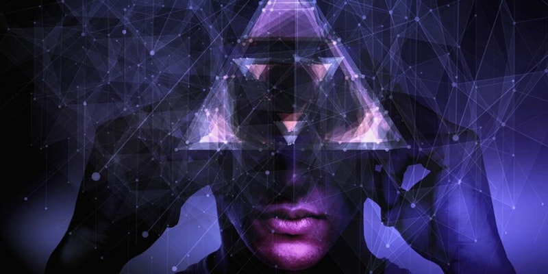 Yüzünde üçgen şeklinde bir desen olan takım elbiseli bir adamın yakın plan görüntüsü. Doğrudan kameraya bakmaktadır ve yüzü ışıkla aydınlatılmıştır. Gözleri tamamen açık ve ağzı hafifçe açık. Beyaz gömlekli ve siyah kravatlı gri bir takım elbise giymektedir. Sol elinde bir tablet bilgisayar tutuyor ve sağ eliyle yüzündeki üçgen şeklindeki bir desene dokunuyor. Yüz ifadesi ciddi ve düşünceli. Saçları koyu renk ve bakımlı. Arka plan sade ve görüntü yalnızca adama, üçgene ve tablete odaklanmış.