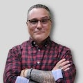 person in a plaid shirt in front of a gray background, in the style of intricate dotwork, queer academia, smilecore, new american color photography, tattoo-inspired, website, optical