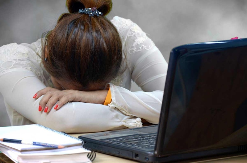 Bir kadın sandalyede oturuyor ve başını ellerinin üzerine koymuş. Saçları mavi bir çiçek tokasıyla arkadan bağlanmış. Tırnakları yumuşak pembe bir renge boyanmış. Yanındaki spiralli defterin üzerinde bir kalem durmaktadır. Arka planda, fotoğrafa bir gizem unsuru katan bulanık bir kalem görüntüsü var. Kadının ifadesi sakin ve memnun. Kendi düşünceleri içinde kaybolmuş, huzurlu bir tefekkür halinde görünüyor. Fotoğrafın ışığı yumuşak ve sıcak, huzurlu bir atmosfer yaratıyor.
