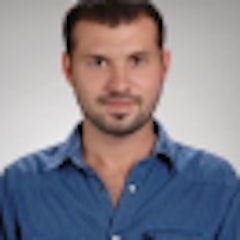 Parlak mavi gömlekli bir adam düz bir arka planın önünde duruyor. Kısa siyah saçları ve temiz traşlı bir yüzü vardır. Elleri arkasında, kameradan uzağa bakmaktadır. Vücudu hafifçe yana dönüktür ve izleyiciye neredeyse profilden bir görünüm verir. Üzerinde beyaz cepli açık mavi yakalı bir gömlek ve koyu mavi bir kot pantolon var. Duruşu rahat ve gevşek bir tavır sergilediğini gösteriyor. İfadesi memnuniyet ve huzur dolu. Gömleğinin mavisi nötr arka planla güzel bir tezat oluşturarak görsel açıdan hoş bir görüntü yaratıyor.