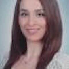Uzun, dalgalı saçları omuzlarından aşağı dökülen kadın gülümsüyor. Yüzünde samimi ve neşeli bir ifade var, gözleri mutlulukla parıldıyor. Yanakları hafifçe kızarmış ve dudakları geniş bir gülümseme şeklinde kıvrılmış. V yakalı, sade, beyaz bir bluz giymiş ve saçlarını düşük bir at kuyruğu şeklinde arkaya toplamış. Arka planda parlak, mavi bir gökyüzü var ve kadının soluk teniyle keskin bir kontrast oluşturuyor. Rahat ve mutlu görünüyor, pozitif enerji ve neşe yayıyor. Pozitif ruh hali bulaşıcıdır ve onu seyretmek gerçekten keyif vericidir.
