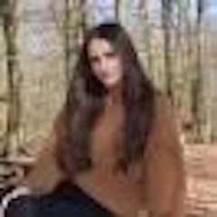 Bu, huzurlu bir ormanda oturan bir kadının çarpıcı bir görüntüsüdür. Kahverengi, uzun kollu bir üst ve mavi kot pantolon giyiyor. Ellerini dizlerinin üzerine koymuş ve meditasyon yapıyormuş gibi gözlerini kapatmış. Güneş onun üzerinde parlıyor, ağaçları ve etrafı aydınlatıyor. Ağaçların canlı yeşili ve yaprakların gürlüğü nefes kesici. Etrafı doğanın güzelliğiyle çevrili ve huzur içinde görünüyor. Bu, doğanın güzelliğini ve dinginliğini anlatan huzurlu bir an.