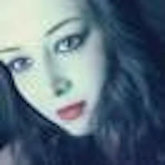 Bu, selfie çeken genç bir kadının yakın plan bir fotoğrafı. Gözleri kapalı ve başı hafifçe yana eğik bir şekilde gülümsüyor. Saçları yüzünden geriye doğru toplanmış ve telefonunu iki eliyle tutuyor. Üzerinde sade beyaz bir tişört ve kolye ucu olan bir kolye var. Arkasındaki ışık yüzünü aydınlatıyor ve cildinin ışıl ışıl görünmesini sağlıyor. Anı yakalarken yüzü neşe ve mutluluk dolu. Arka plan hafifçe bulanıklaştırılarak odağın kadının yüzünde ve selfie çekme eyleminde kalması sağlanmış. Bu görüntü, zaman içinde bir anı yakalamanın ve onu tekrar tekrar yaşayabilmenin sevincinin harika bir temsilidir.