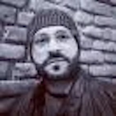 Bu, koyu renkli bere takan bir adamın görüntüsüdür. İyi aydınlatılmış bir odada ayakta durmakta ve kameraya bakmaktadır. Yüzünde nötr bir ifade var ve koyu renkli kapüşonlu bir sweatshirt giyiyor. Saçları koyu renk ve kısa kesilmiş. Bere açık gri renktedir ve başını ve kulaklarını örter. Elleri yanlarında ve rahat bir duruşta duruyor. Kendinden emin ve kontrollü görünüyor. Yirmili yaşlarının sonunda ya da otuzlu yaşlarının başında gibi görünüyor. Beresi klasik bir tarz ve ona havalı, rahat bir görünüm veriyor.