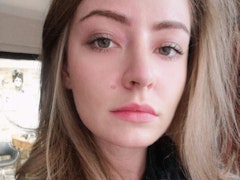 Genç bir kadın büyük bir pencerenin önünde selfie çekiyor. Gülümsüyor ve telefonunu bir elinde tutarak doğrudan kameraya bakıyor. Saçları at kuyruğu şeklinde geriye doğru toplanmış ve üzerinde beyaz bir tişört var. Güzel bronz bir teni ve parlak, parıldayan gözleri var. Rahat ve mutlu görünüyor, telefonuyla görüntüsünü çekerken anın tadını çıkarıyor. Diğer eli pencerenin pervazında duruyor ve pencereden içeri giren güneş ışığı yüzünü ve arka planı aydınlatıyor.