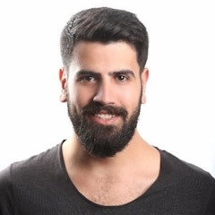 Bu, dolgun ve kalın sakallı yetişkin bir erkeğin yakın çekim görüntüsüdür. Doğrudan kameraya bakarken yüz ifadesi rahatlamış görünüyor. Sakalları düzgünce kesilmiş ve çoğunlukla koyu kahverengi, ancak alt kısma yakın birkaç açık renkli saç teli görülebiliyor. Gözleri kahverenginin sıcak bir tonunda ve dudakları hafifçe ayrık. Cildi pürüzsüz ve berrak, saçları kısa ve bakımlı görünüyor. Sakalının koyu renkleriyle iyi bir kontrast oluşturan sade beyaz bir tişört giyiyor. Genel olarak, bu sakallı ve bakımlı bir adamın huzurlu ve kendinden emin bir portresi.